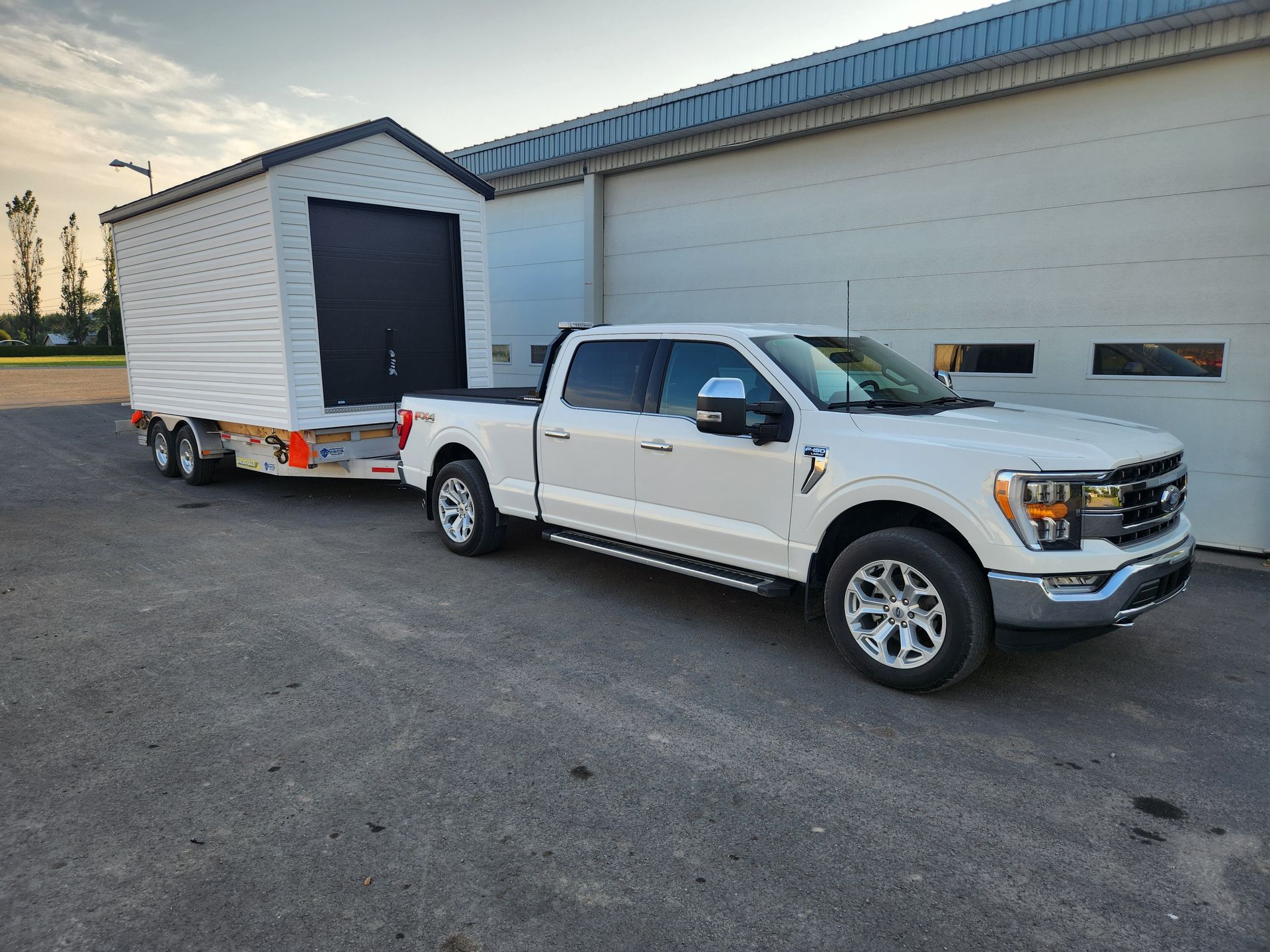 Un camion blanc tire une remorque avec un hangar attaché.