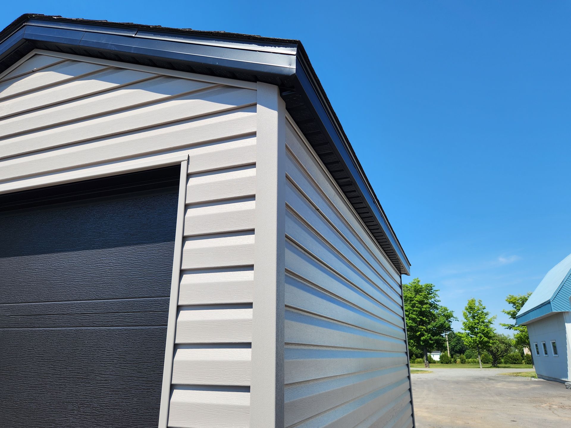 Un garage avec une porte de garage noire et un revêtement blanc
