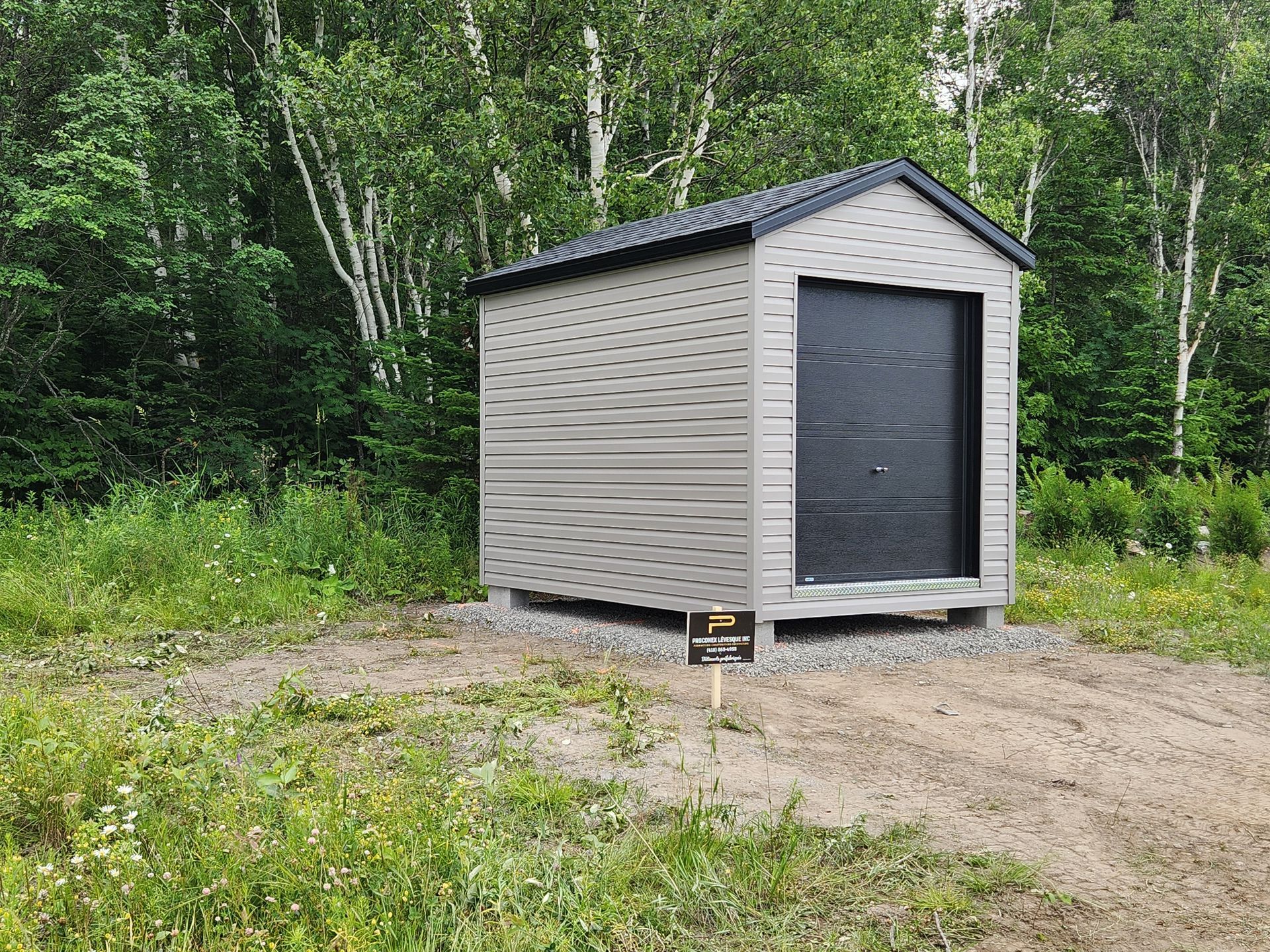 Un petit hangar se trouve au milieu d'un champ herbeux.