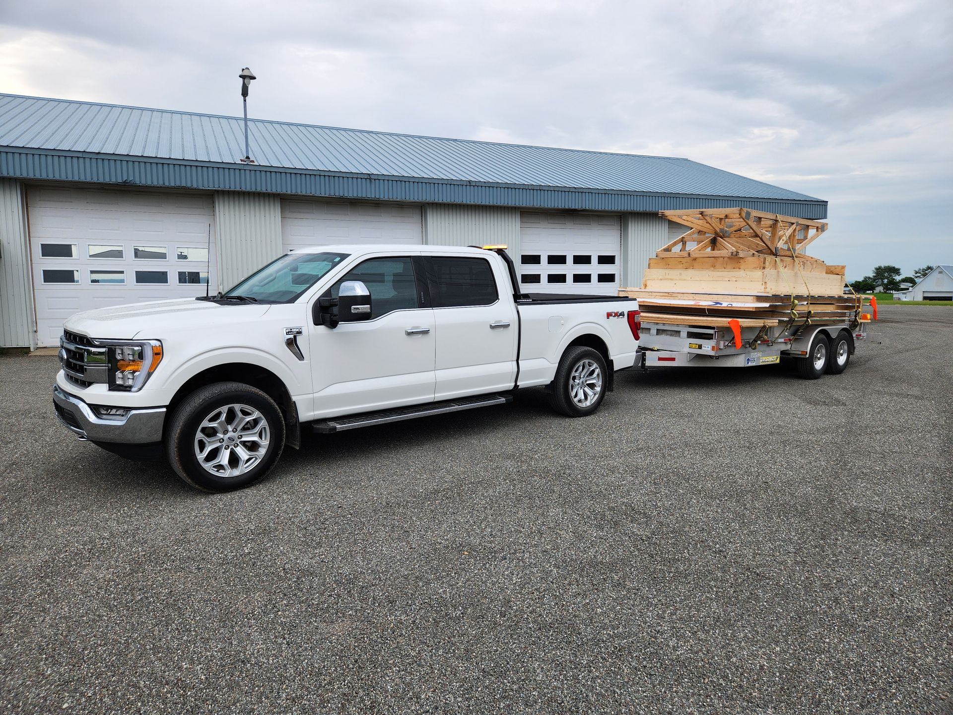 Un camion blanc tire une remorque avec du bois dessus.