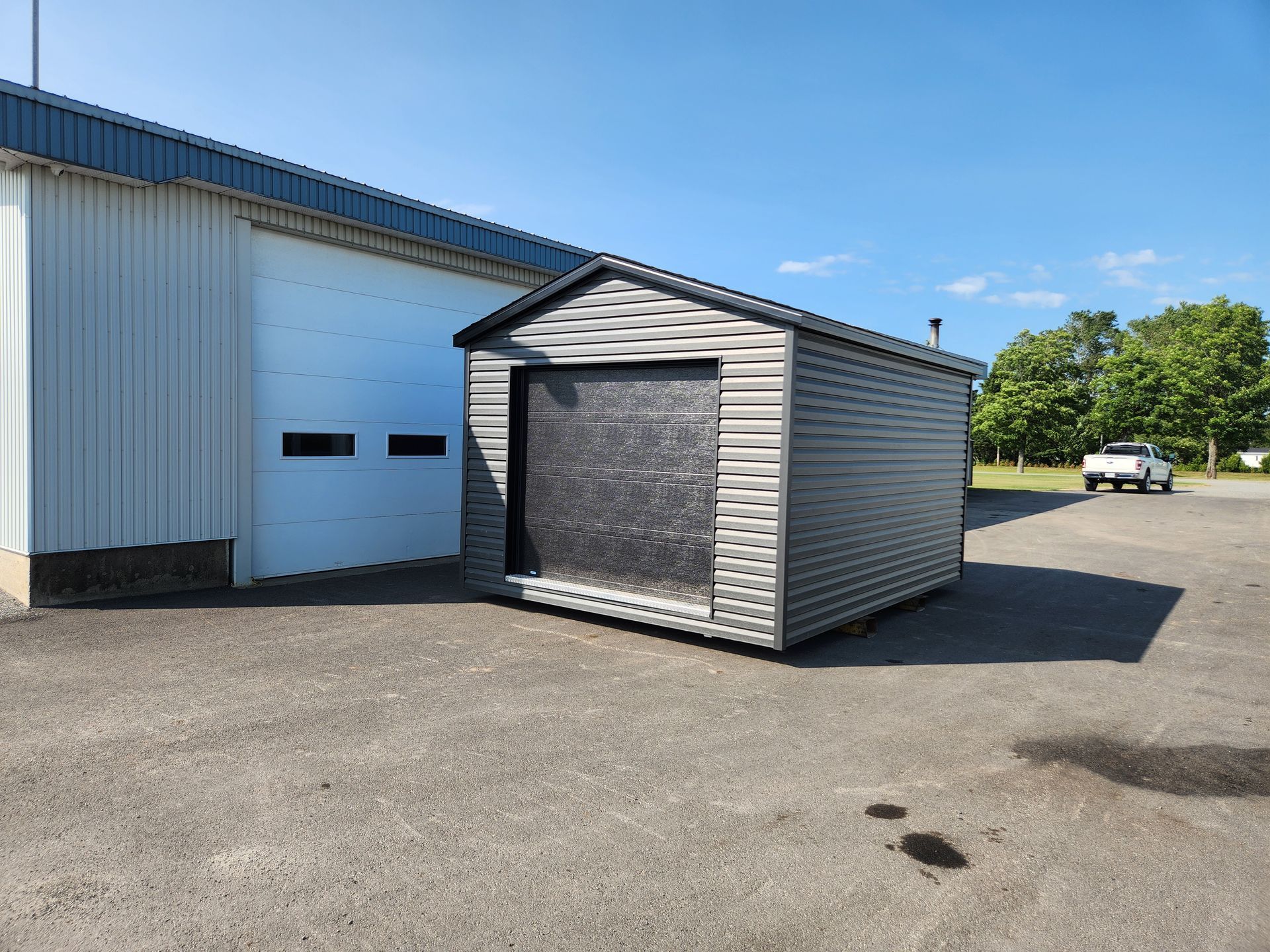 Un hangar est assis dans un parking devant un bâtiment.