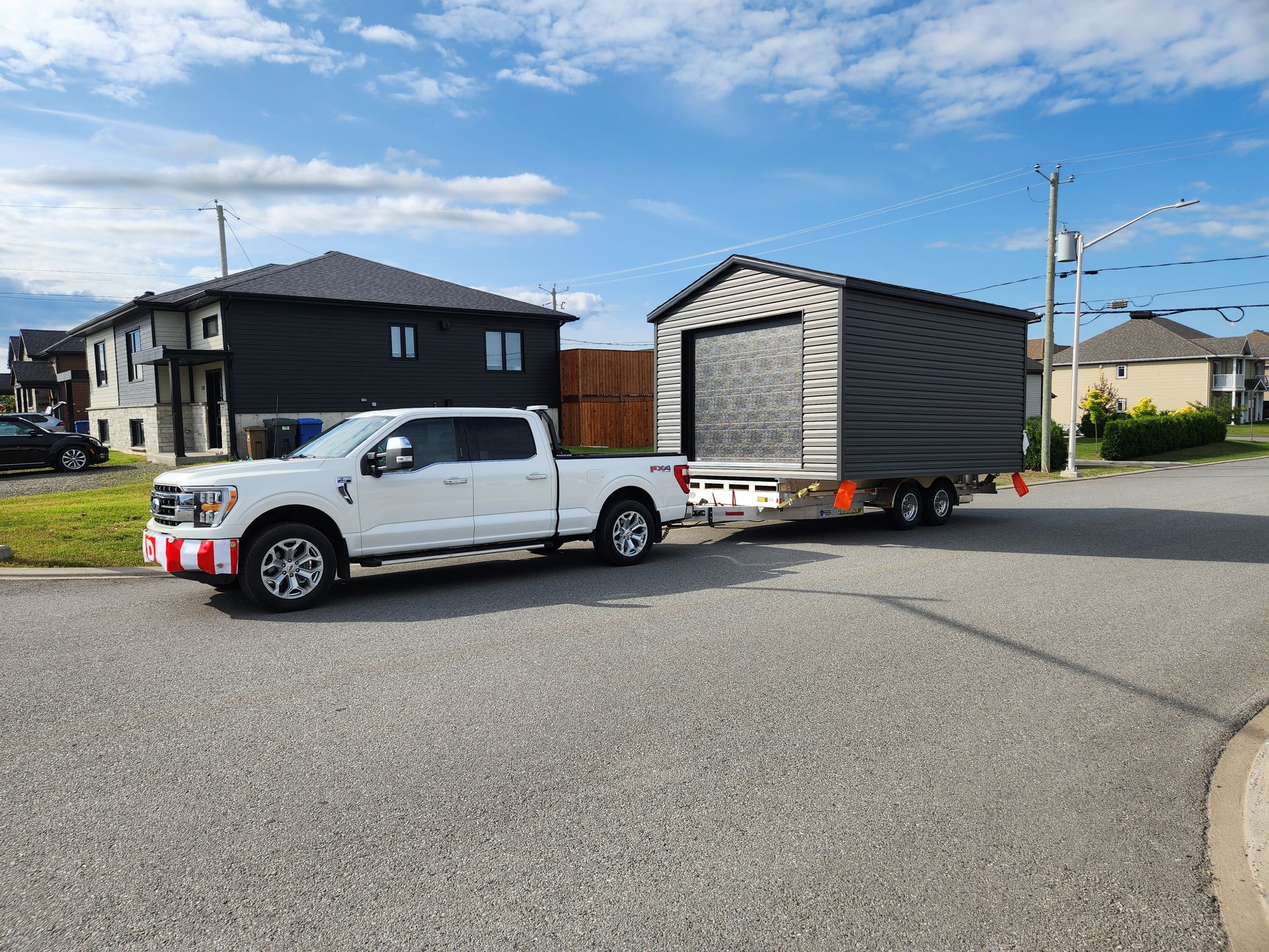 Un camion blanc tire une remorque avec un hangar dessus.