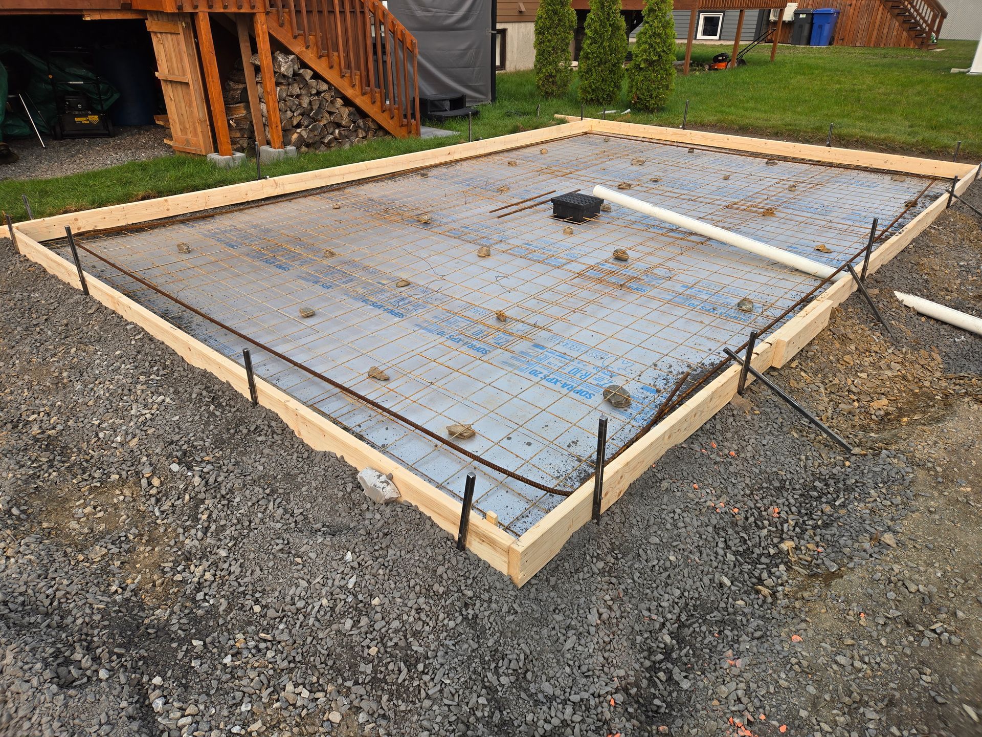 Une fondation en béton est en cours de construction dans l'arrière-cour d'une maison.