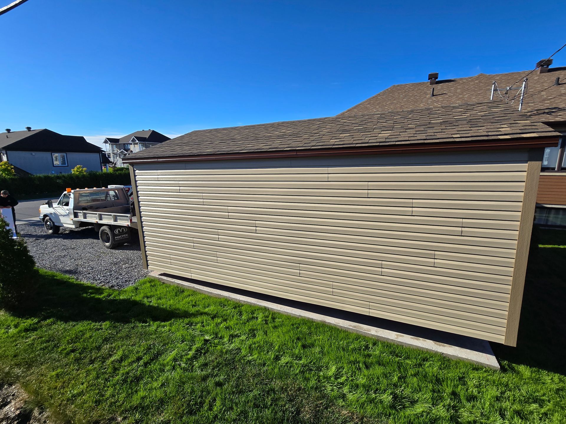 Un camion blanc est garé devant un garage au toit marron.