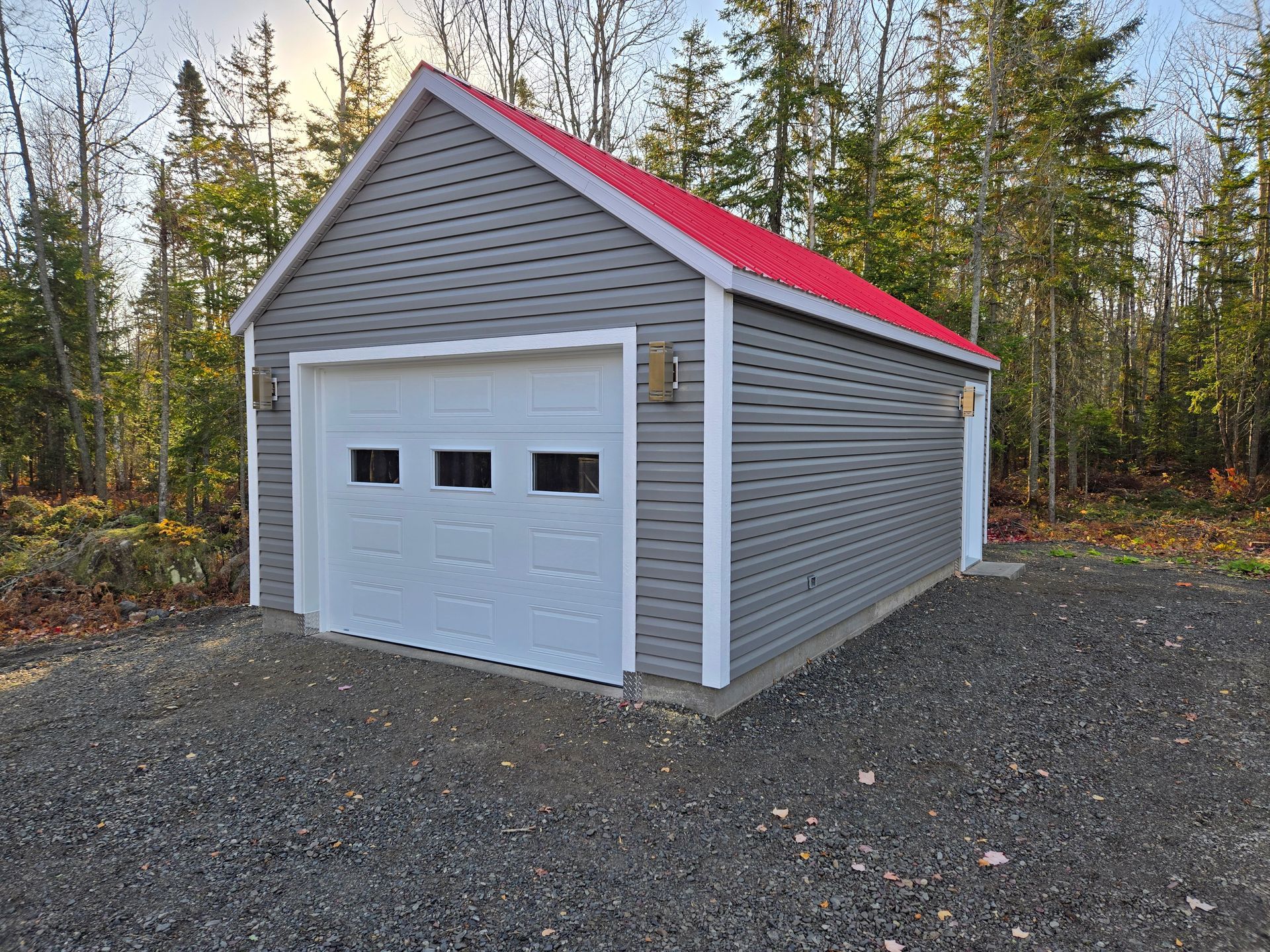 Un garage au toit rouge se trouve au milieu d'une forêt.