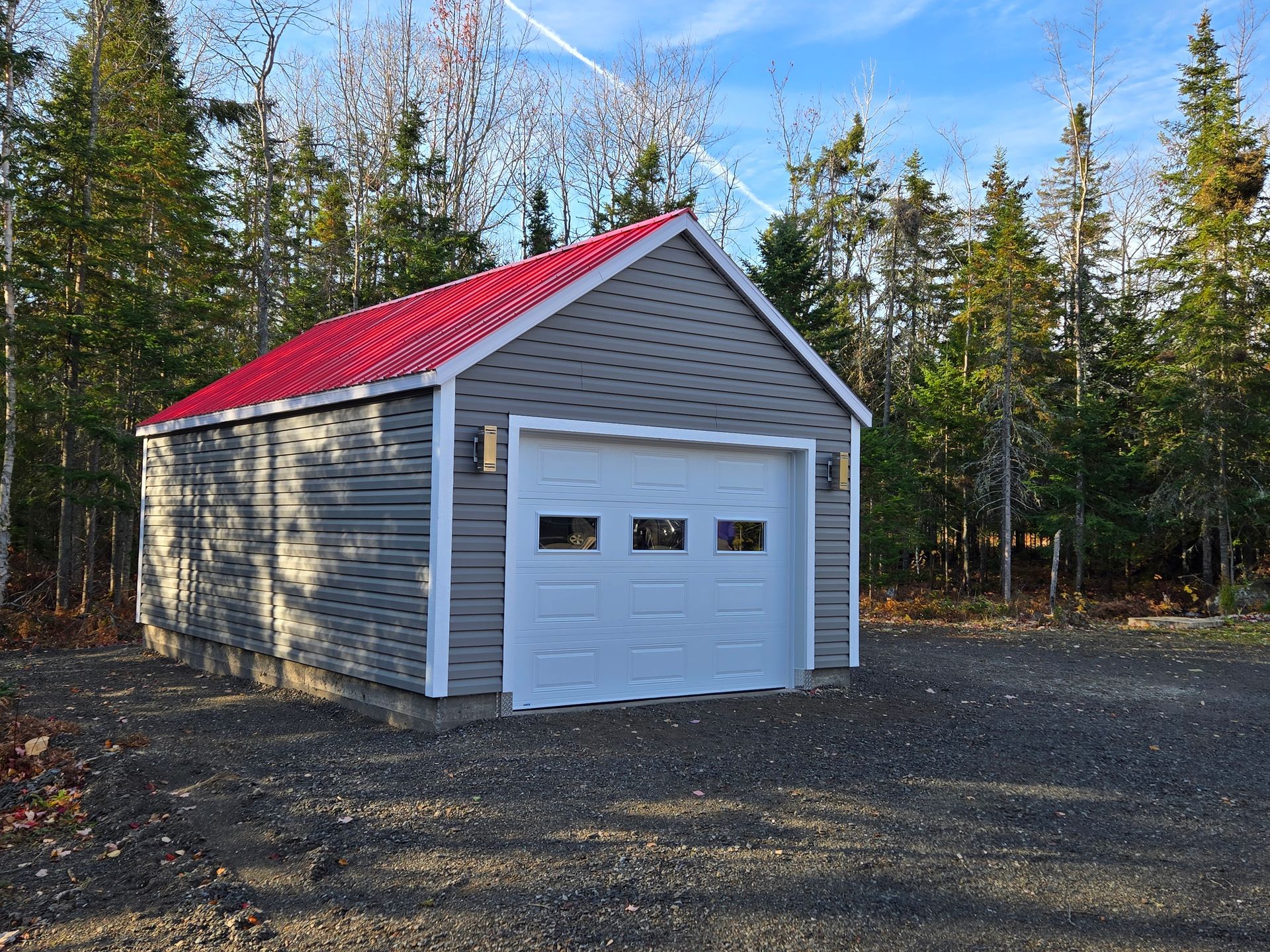 Un garage au toit rouge se trouve au milieu d'une forêt.