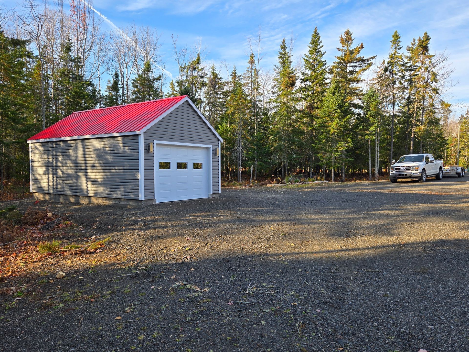 Un camion blanc est garé devant un garage au toit rouge.