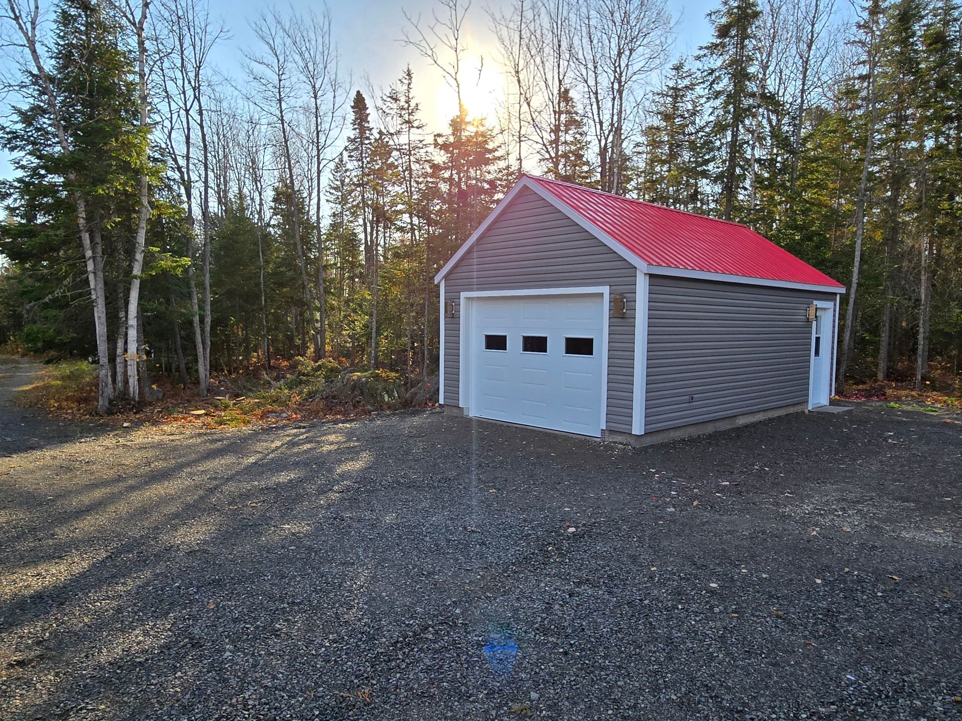 Un garage au toit rouge se trouve au milieu d'une forêt.