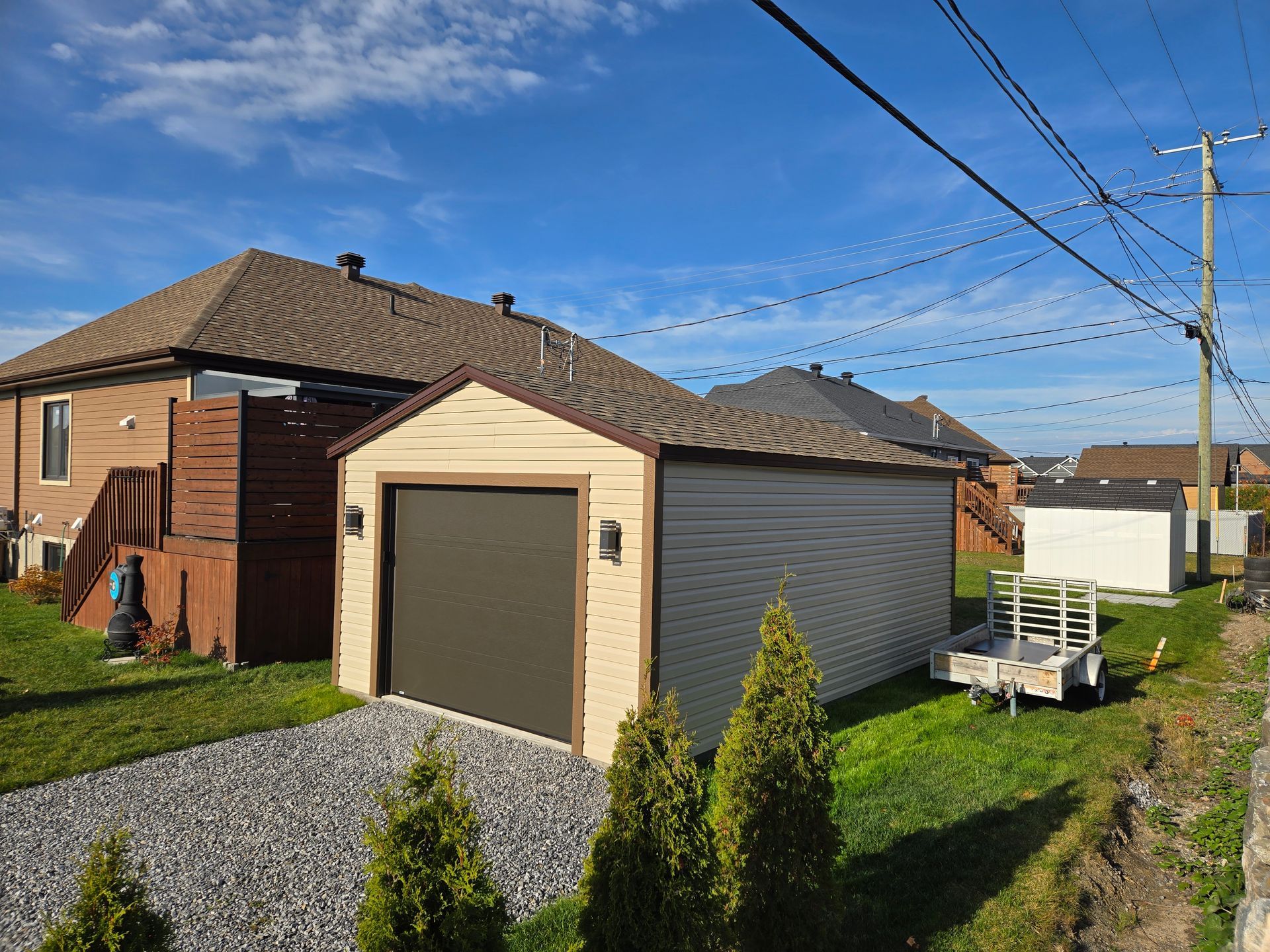 Un petit garage avec une remorque garée devant une maison.
