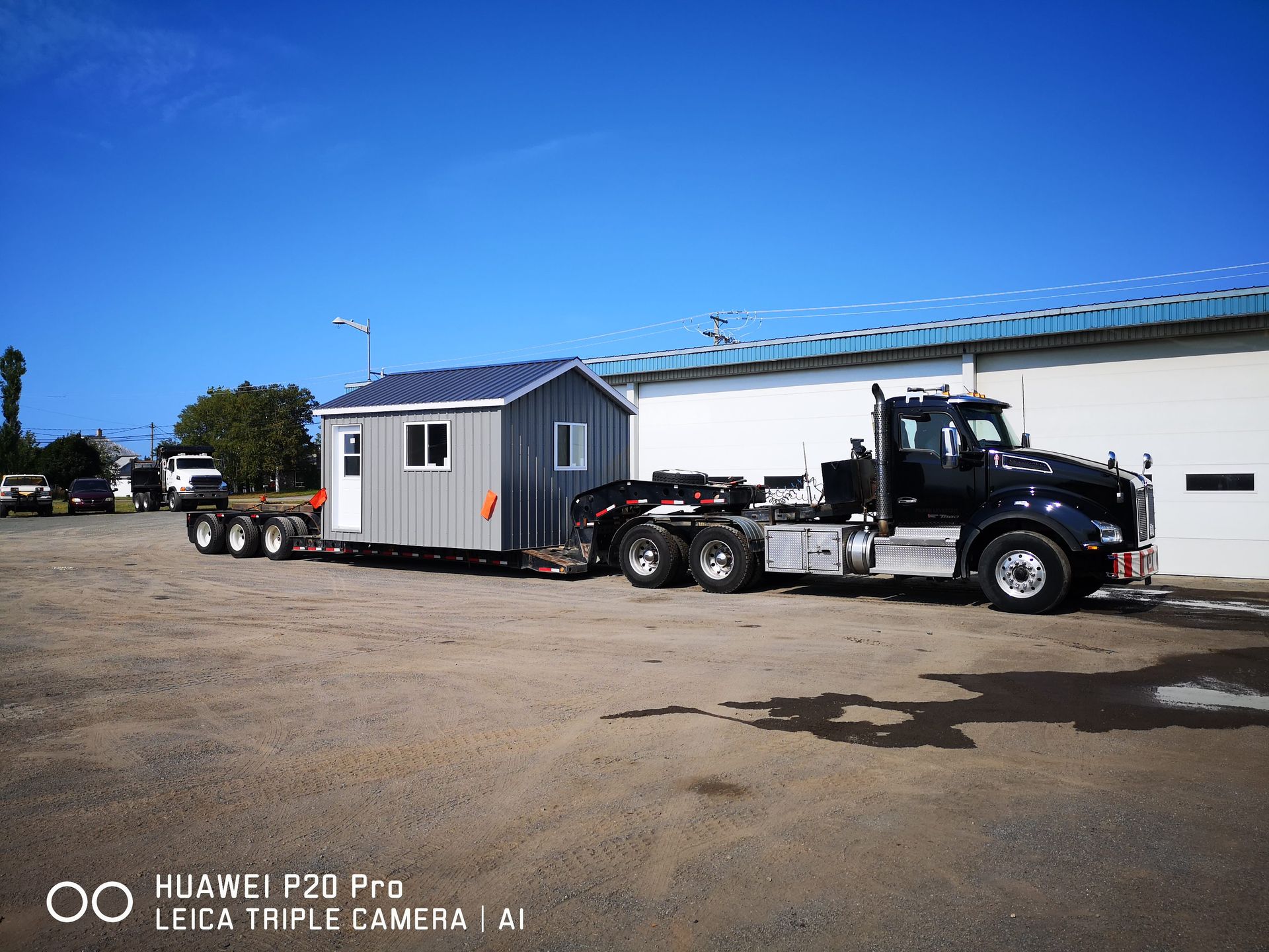 Un camion tire une remorque avec un hangar dessus.