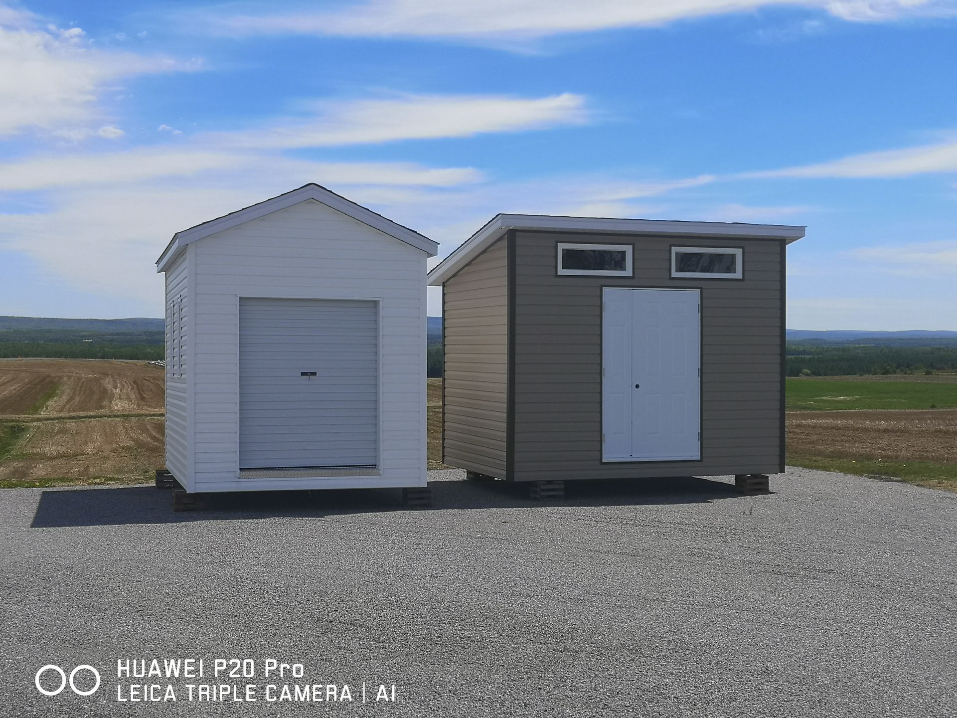 Deux hangars sont situés l'un à côté de l'autre sur un chemin de gravier.