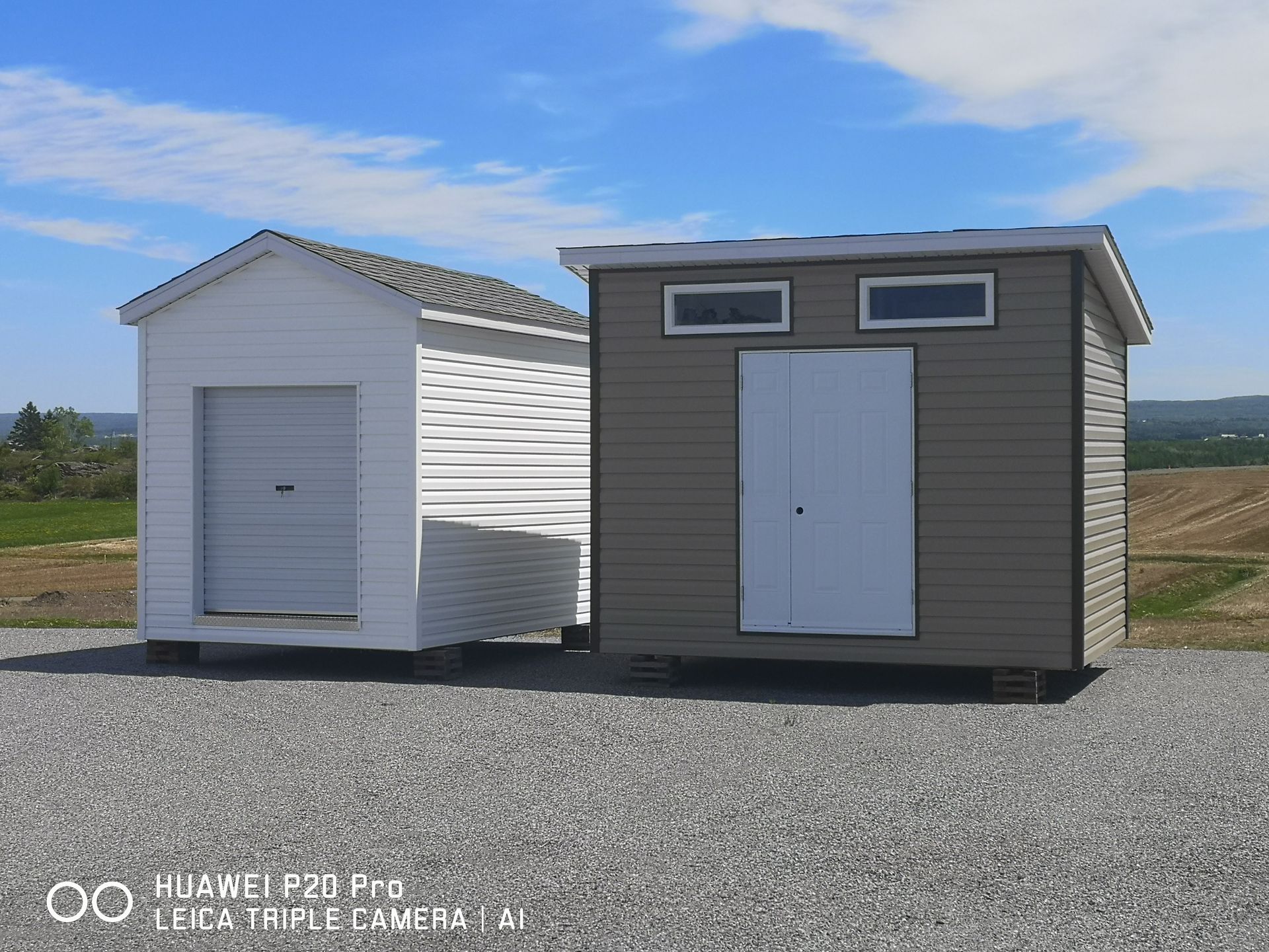 Deux hangars sont situés l'un à côté de l'autre sur un terrain en gravier.