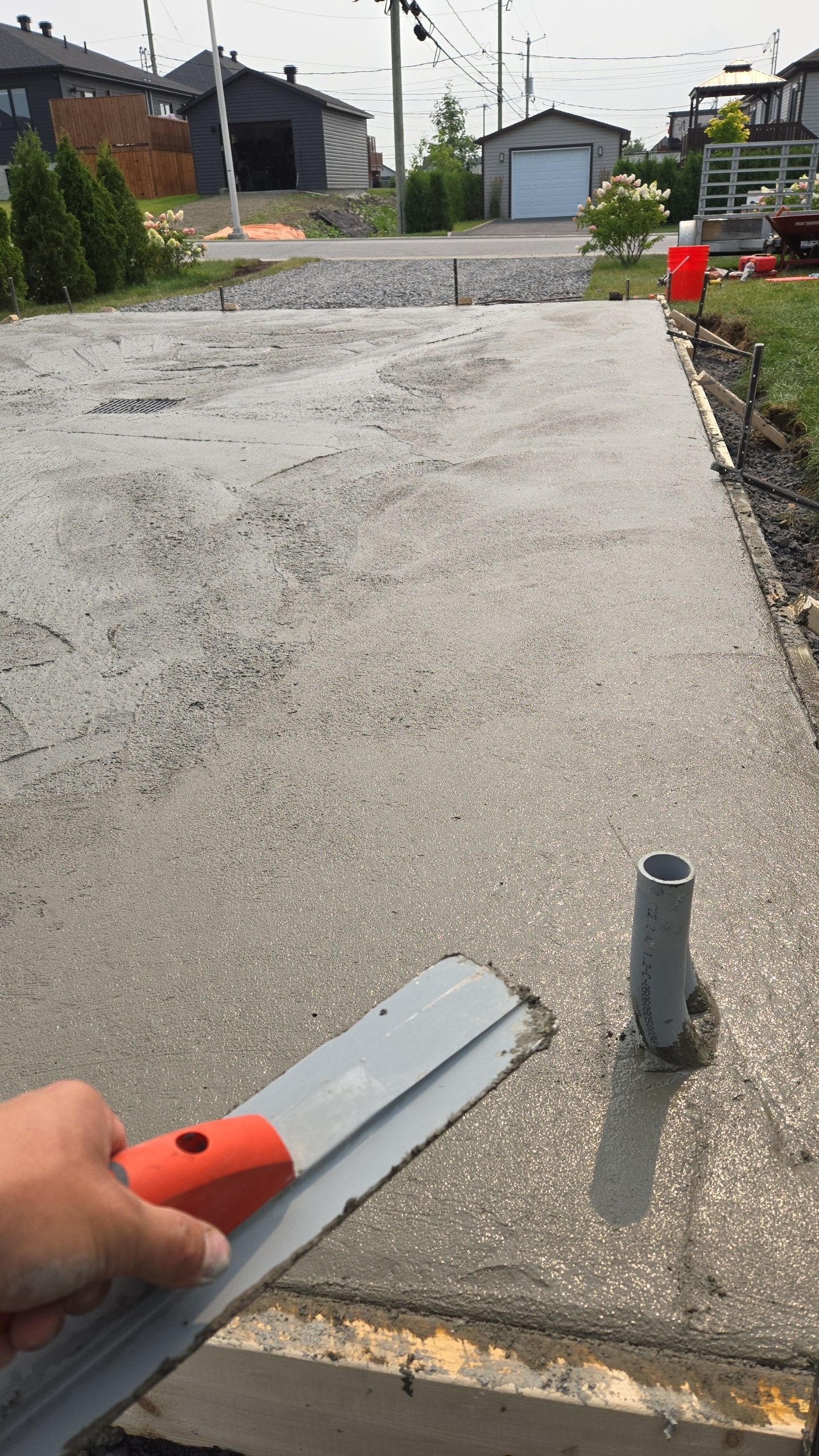 Une personne utilise une truelle pour niveler un trottoir en béton.