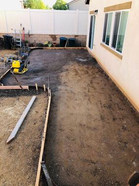 A concrete patio is being built in the backyard of a house in Beaumont, CA.