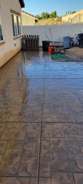 A patio with a fence and a hose in front of a house.