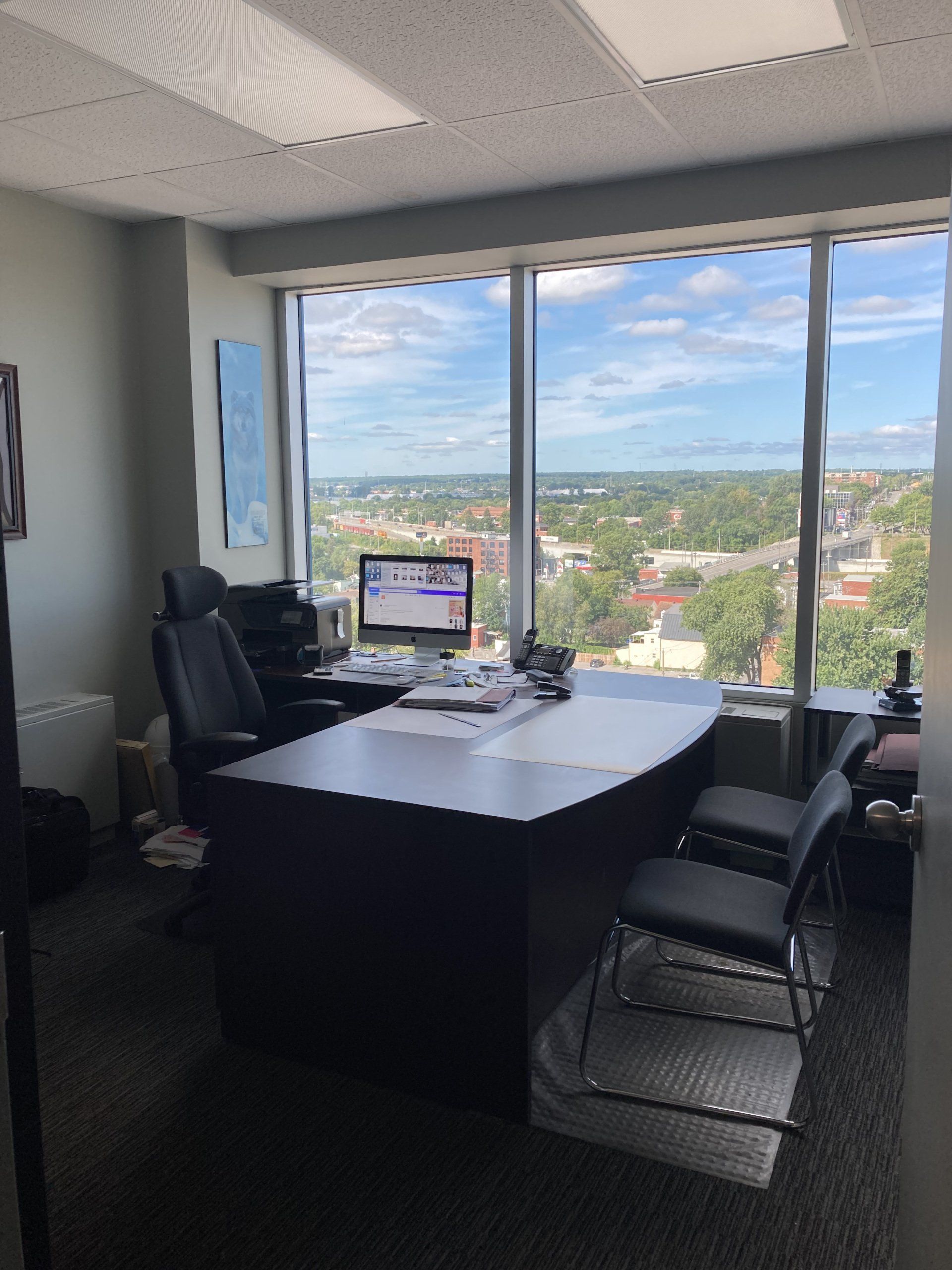 Un bureau avec une grande fenêtre et un bureau avec un ordinateur dessus