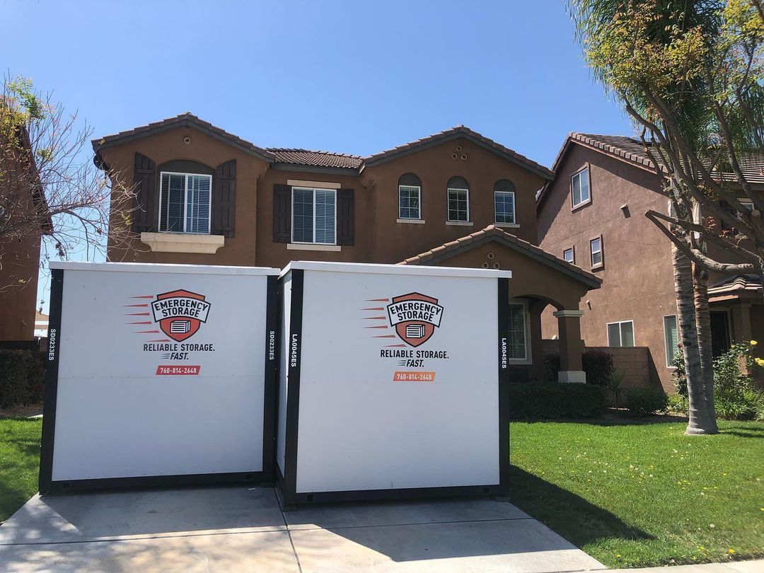 Two portable storage containers are parked in front of a house.