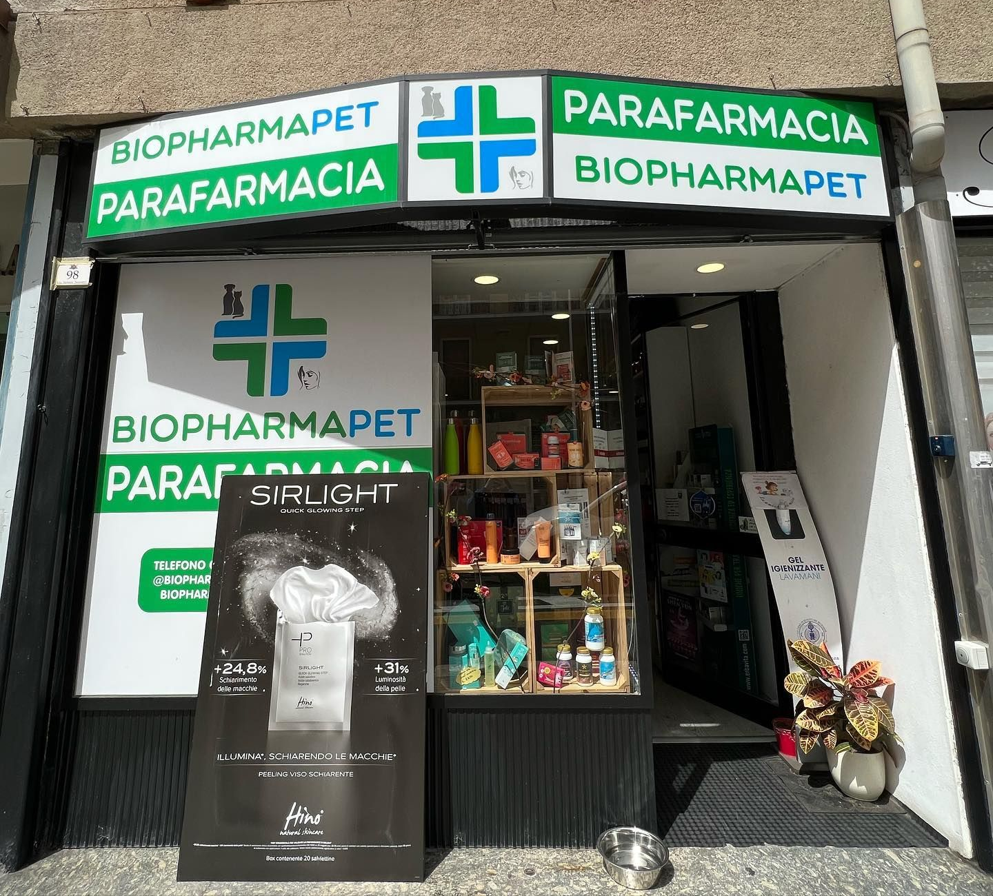 La vetrina di una farmacia veterinaria con insegne verdi e bianche. Davanti c'è una pubblicità di un prodotto.
