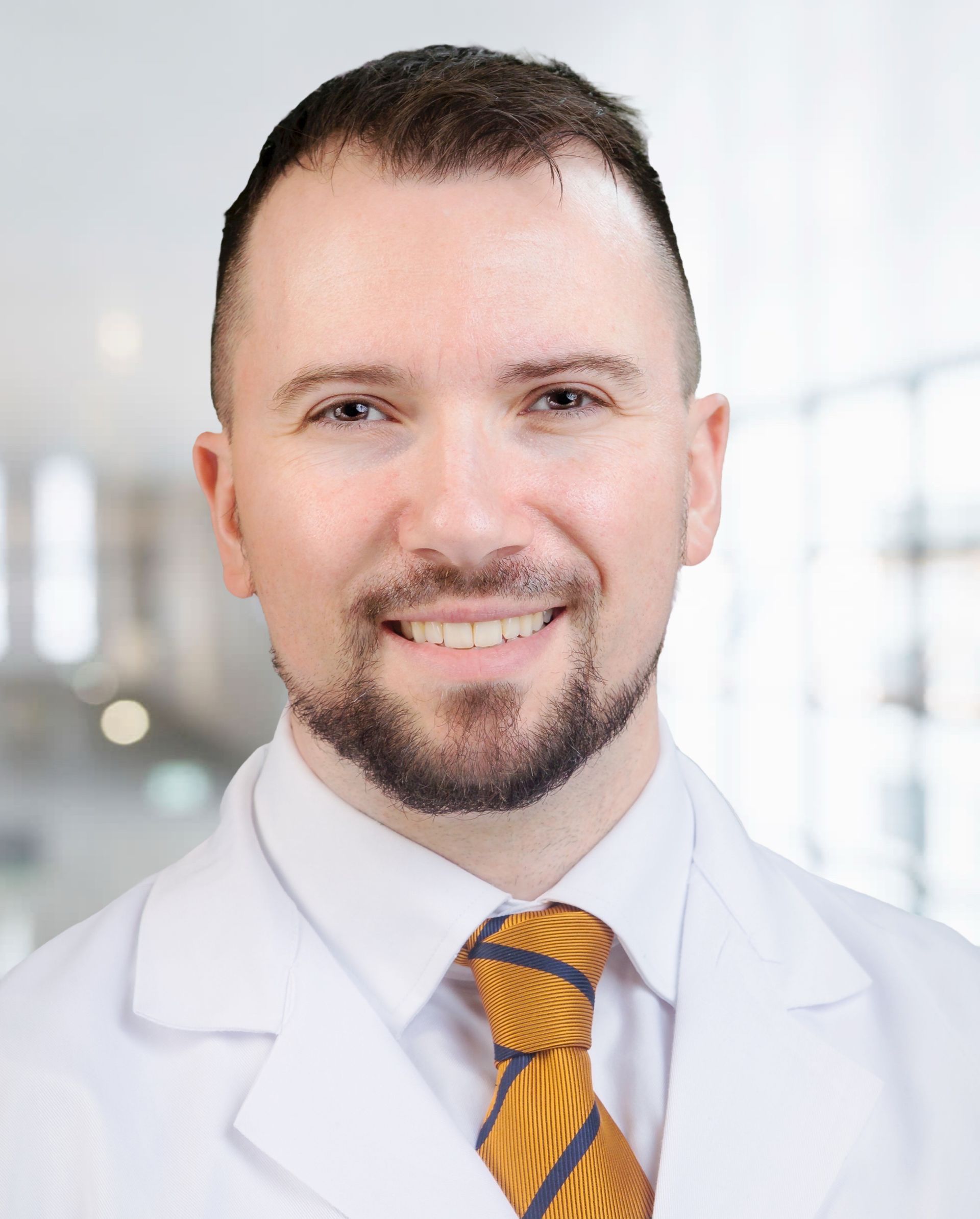 A man in a white coat with a stethoscope around his neck