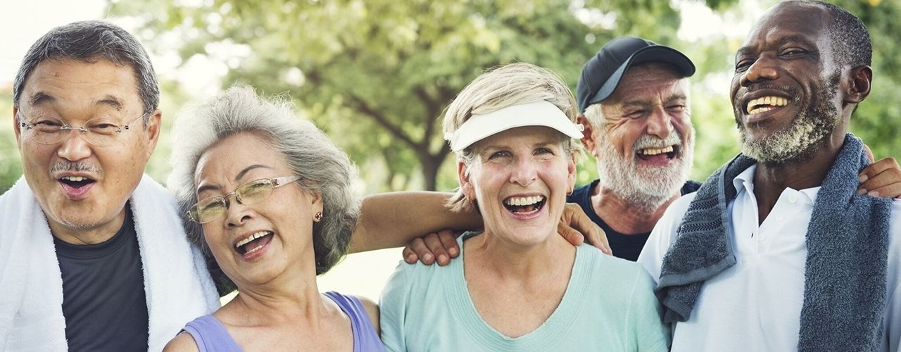 A group of elderly people are standing next to each other and smiling.