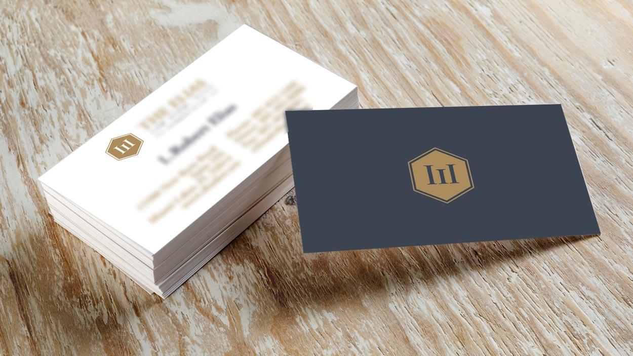 Two business cards are stacked on top of each other on a wooden table.