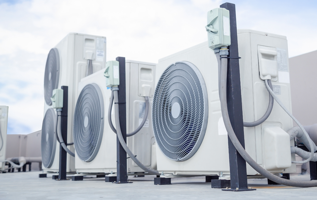A row of air conditioners sitting on top of a roof.