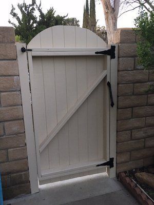 A white wooden gate is sitting in front of a brick wall.