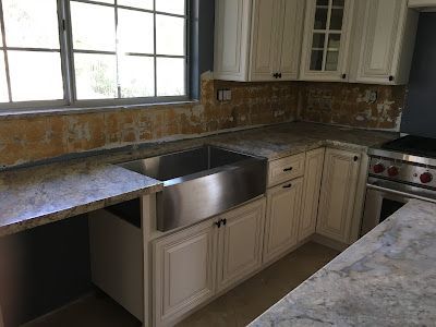 A kitchen with white cabinets and a stainless steel sink.