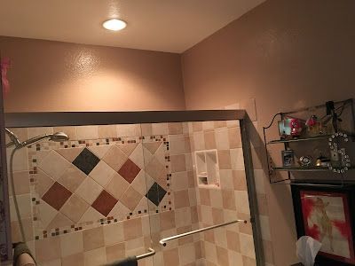 A bathroom with a walk in shower and a tiled wall.