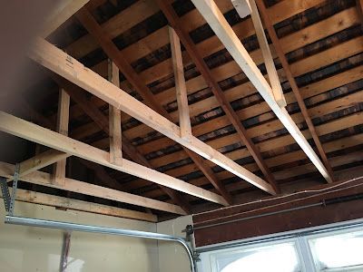 The ceiling of a garage with wooden beams and a garage door.