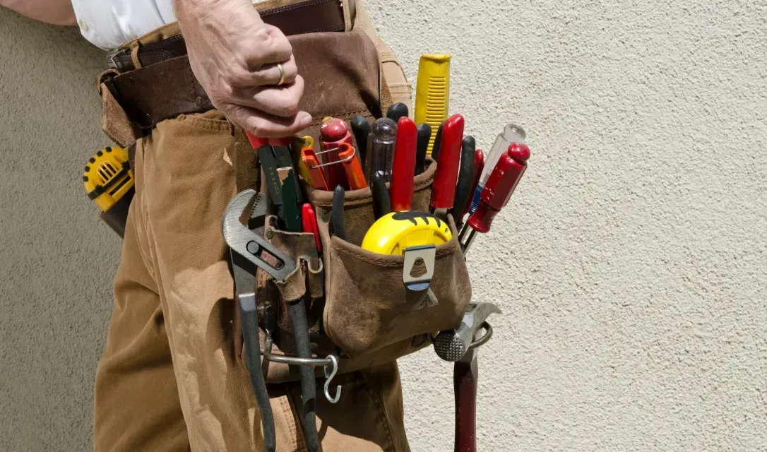 A man is wearing a tool belt filled with tools.