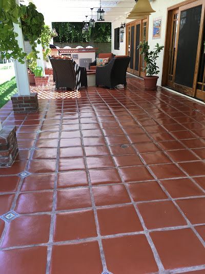 A patio with a red tile floor and chairs