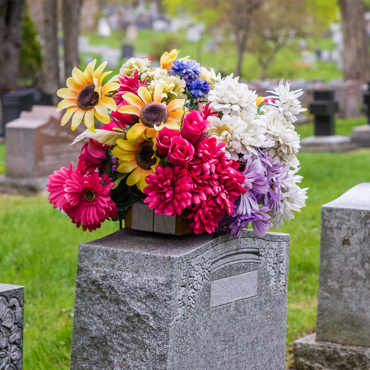 A bouquet of flowers is sitting on top of a grave in a cemetery.