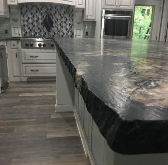 A kitchen with a large granite counter top and white cabinets.