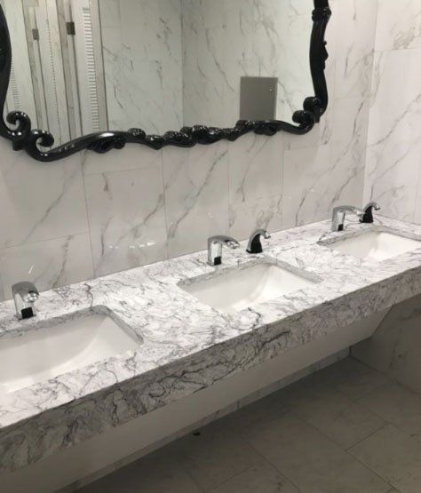A bathroom with two sinks , a mirror and a marble counter top.