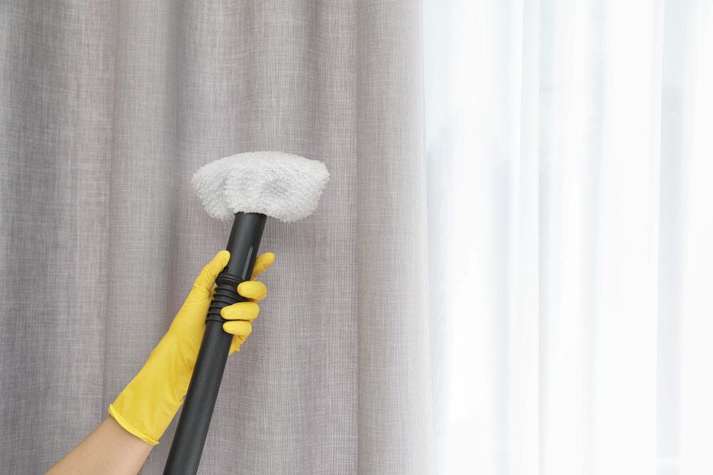 A Person Wearing Yellow Gloves Is Cleaning Curtains With A Duster - Carpet 2 Couch in Condon, QLD