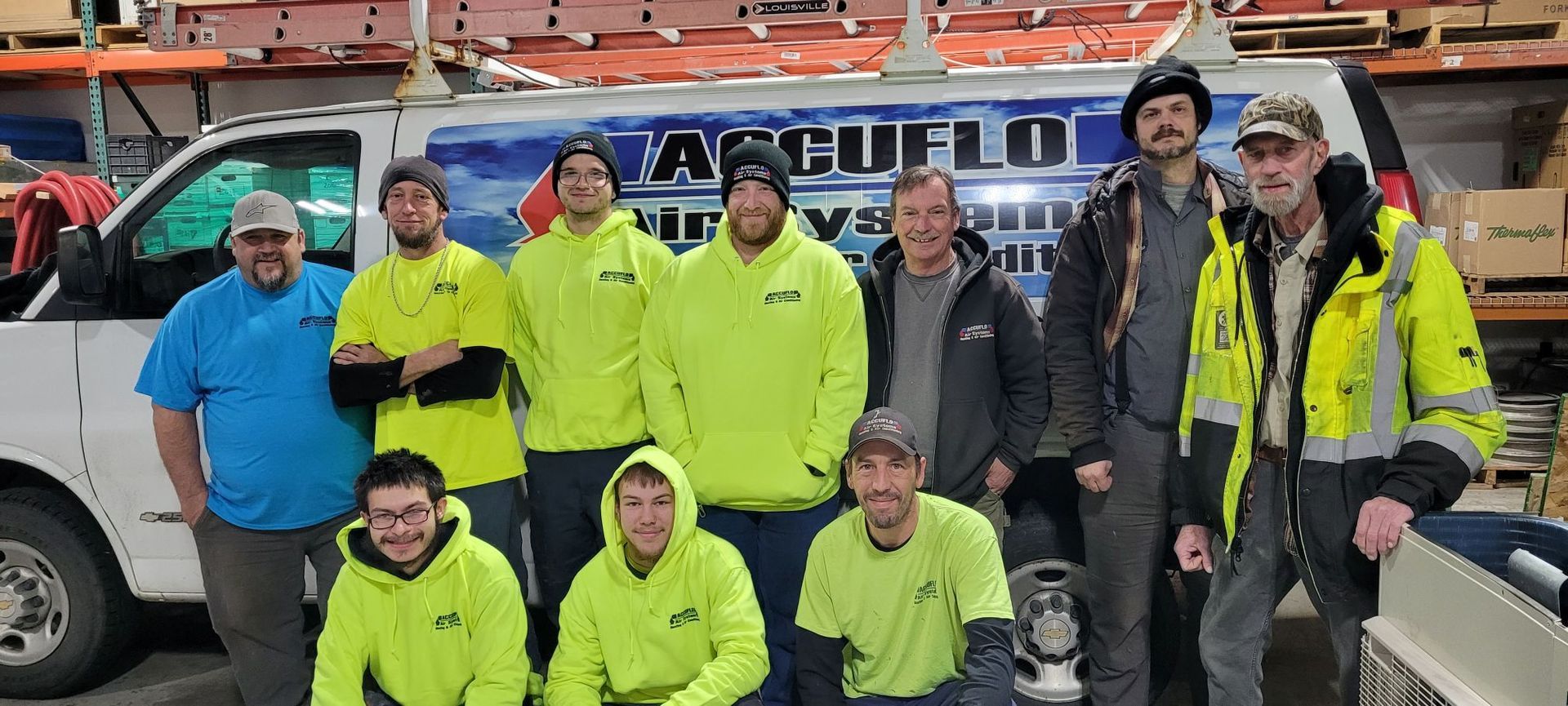 A group of ten people wearing work attire pose in front of a white service van labeled 