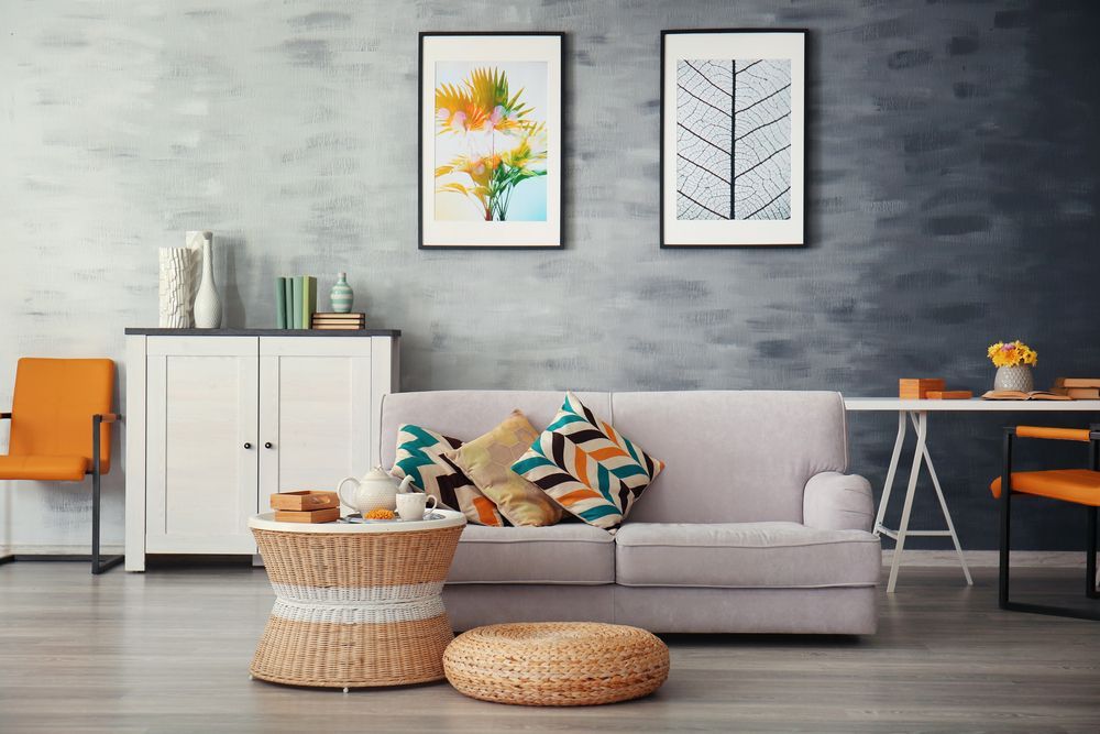 Living room with gray sofa, artwork, and woven coffee table.