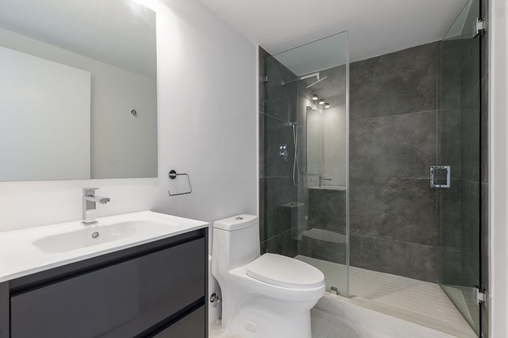 Modern bathroom with a gray shower, white toilet, and dark gray vanity.