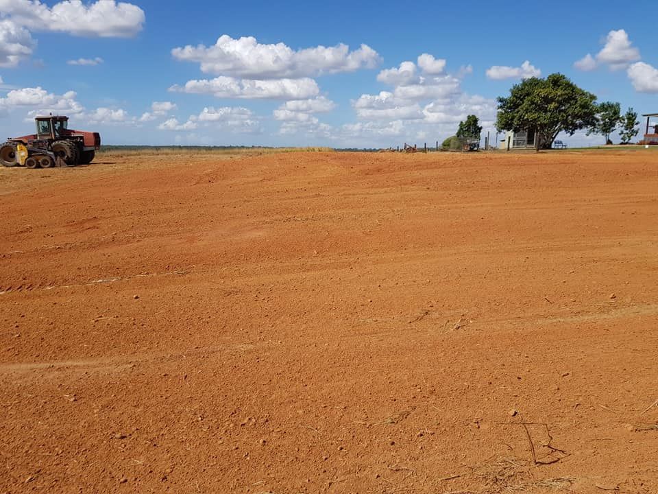 A Tractor is Plowing a Dirt Field With a Tree in the Background — B E Laser Levelling QLD in Rockhampton, QLD