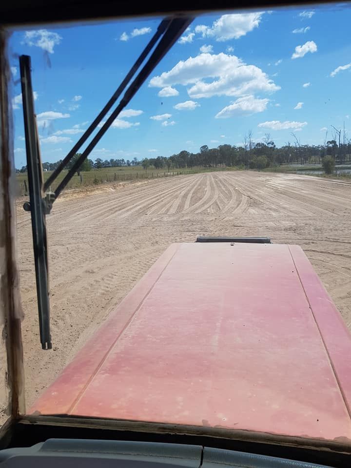 A Tractor is Driving Through a Dirt Field on a Sunny Day — B E Laser Levelling QLD in Bundaberg, QLD