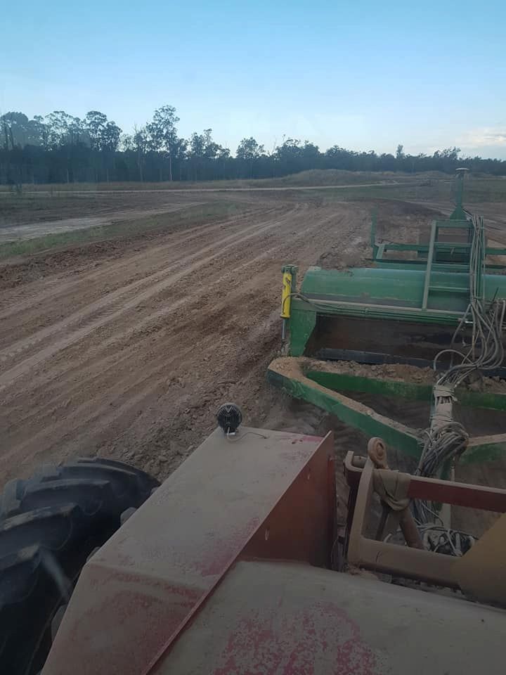 A Tractor is Plowing a Dirt Road in a Field — B E Laser Levelling QLD in Bundaberg, QLD