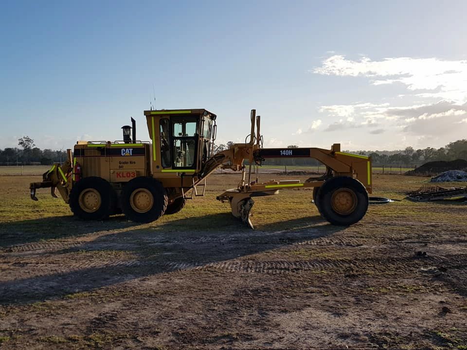 A Yellow Tractor is Parked in a Dirt Field — B E Laser Levelling QLD in Rockhampton, QLD