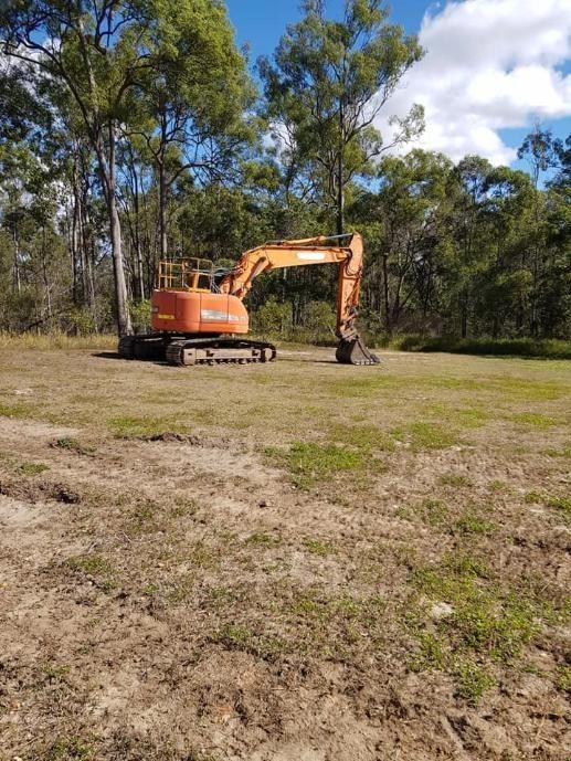A Large Orange Excavator is Sitting in the Middle of a Field — B E Laser Levelling QLD in Bundaberg, QLD