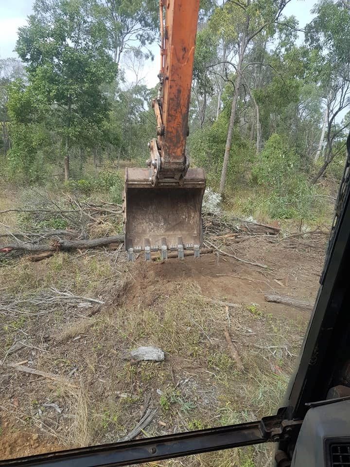 A Large Excavator is Digging a Hole in the Middle of a Forest — B E Laser Levelling QLD in Bucca, QLD