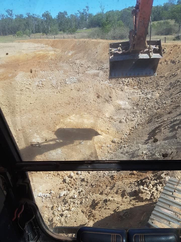 A Bulldozer is Digging a Hole in a Dirt Field — B E Laser Levelling QLD in Gympie, QLD