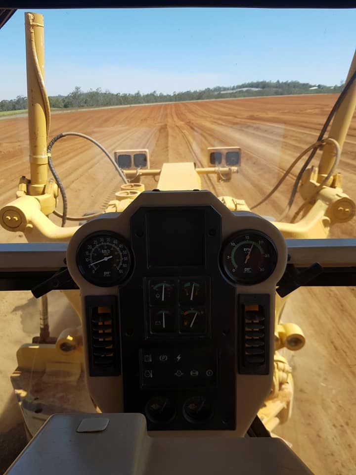 A Bulldozer is Driving Through a Dirt Field — B E Laser Levelling QLD in Bucca, QLD