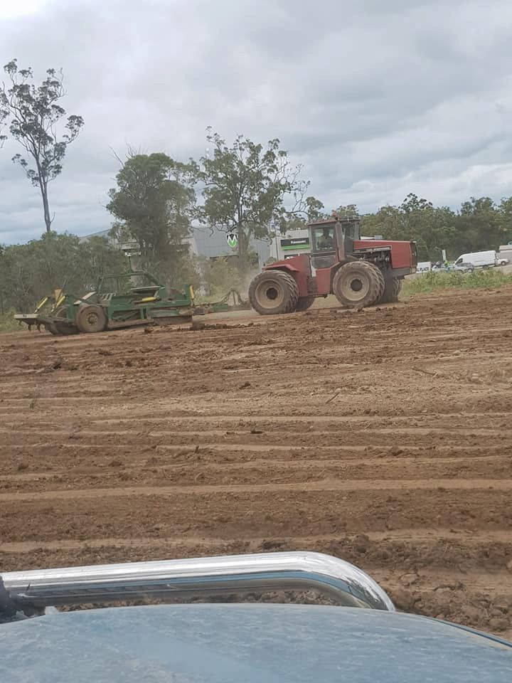 A Red Tractor is Plowing a Dirt Field — B E Laser Levelling QLD in Gympie, QLD