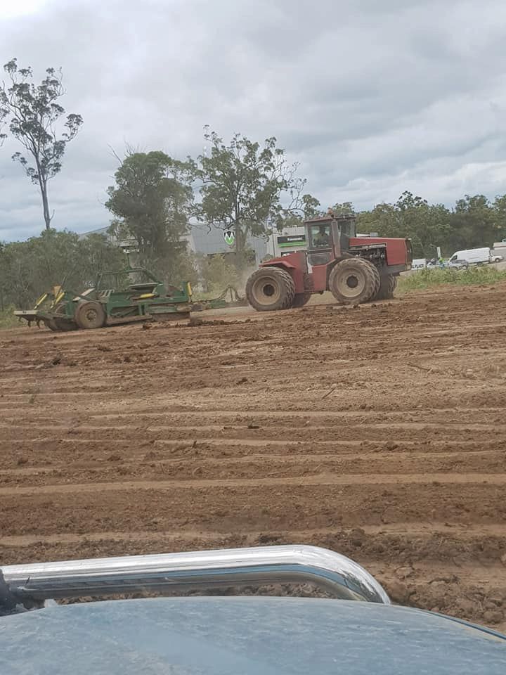 A Red Tractor is Plowing a Dirt Field — B E Laser Levelling QLD in Bucca, QLD