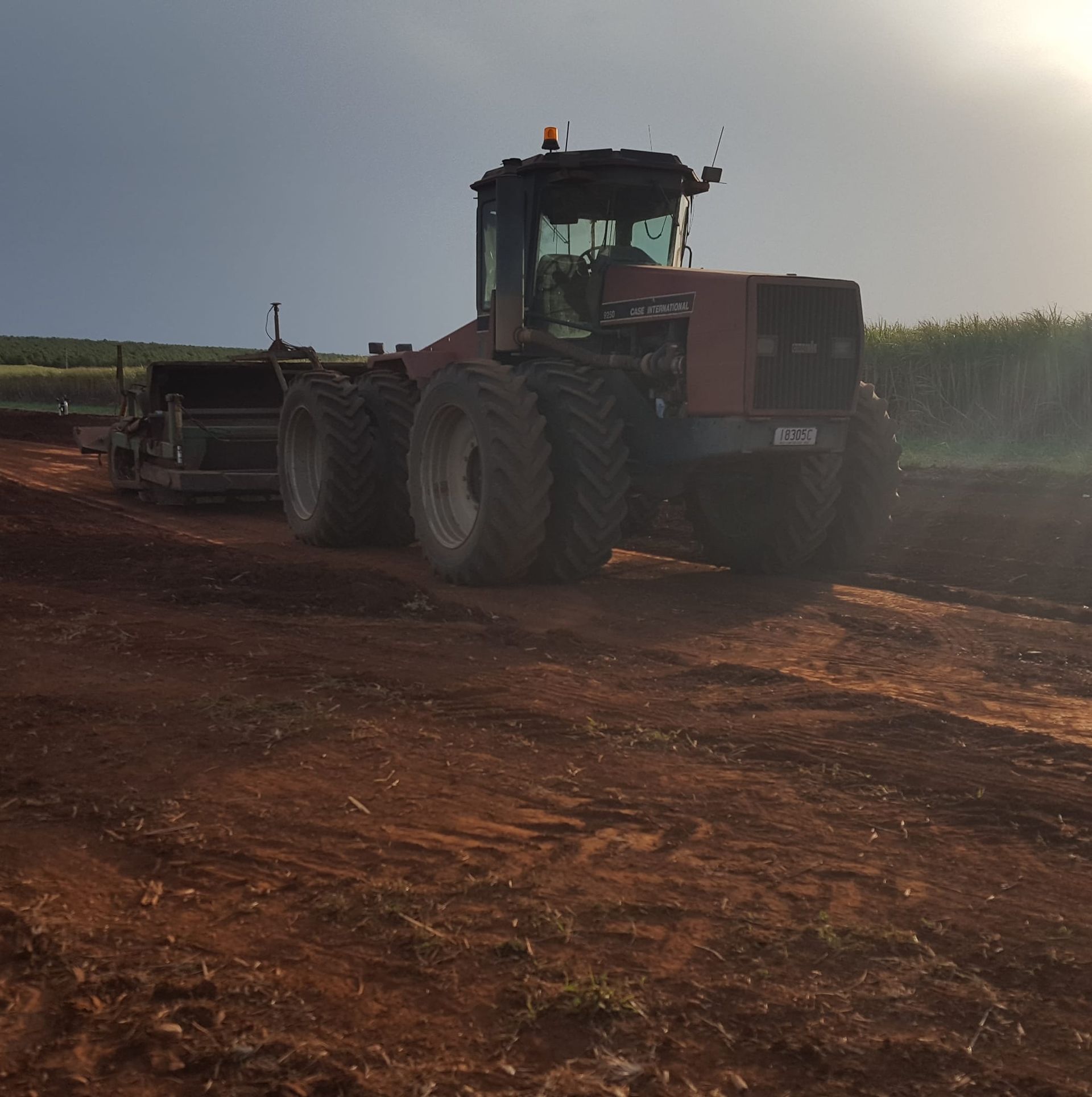 A large red tractor is parked on a dirt road — B E Laser Levelling QLD in Bucca, QLD